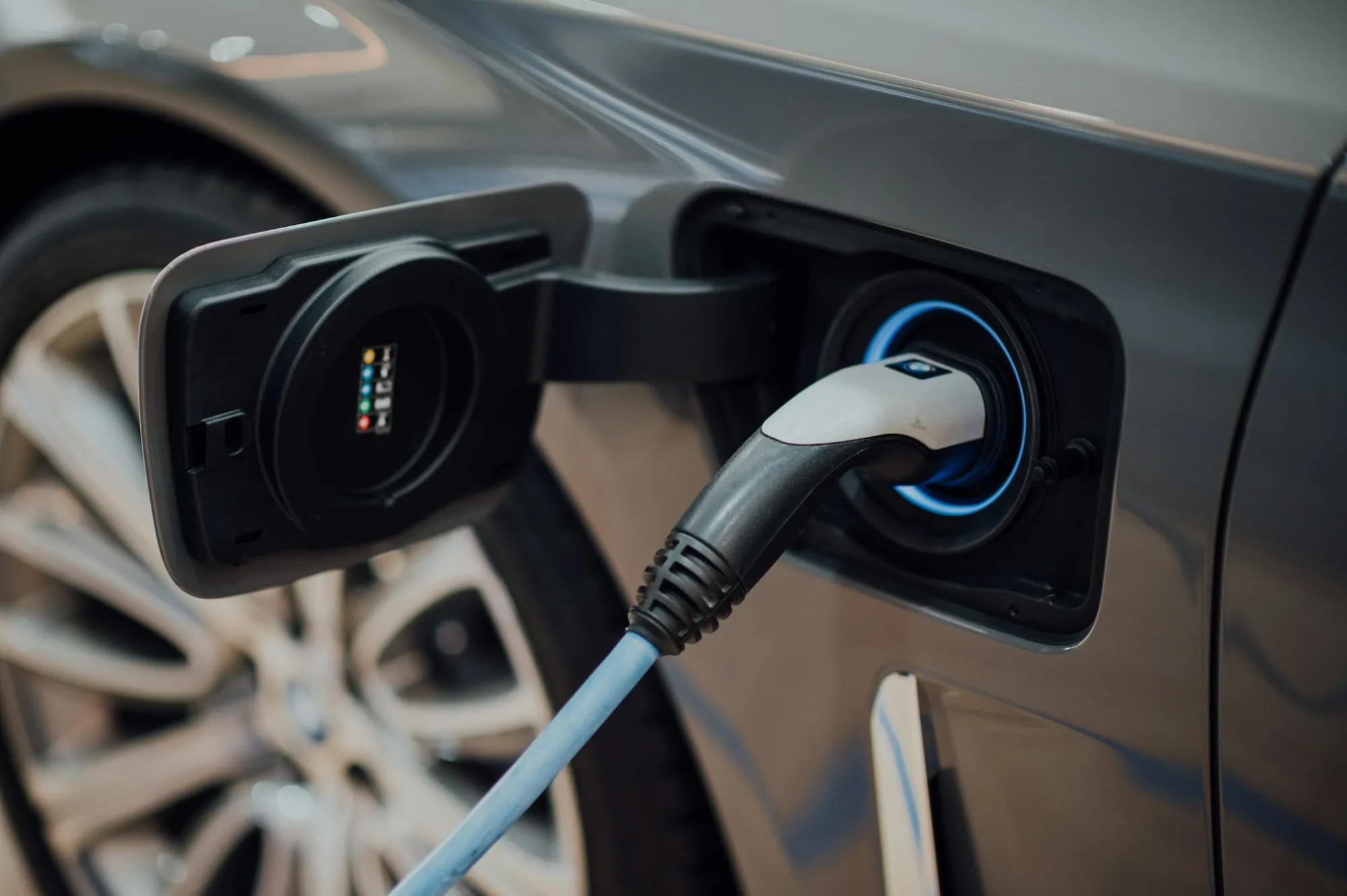 Charging cable connected to the port of a gray car
