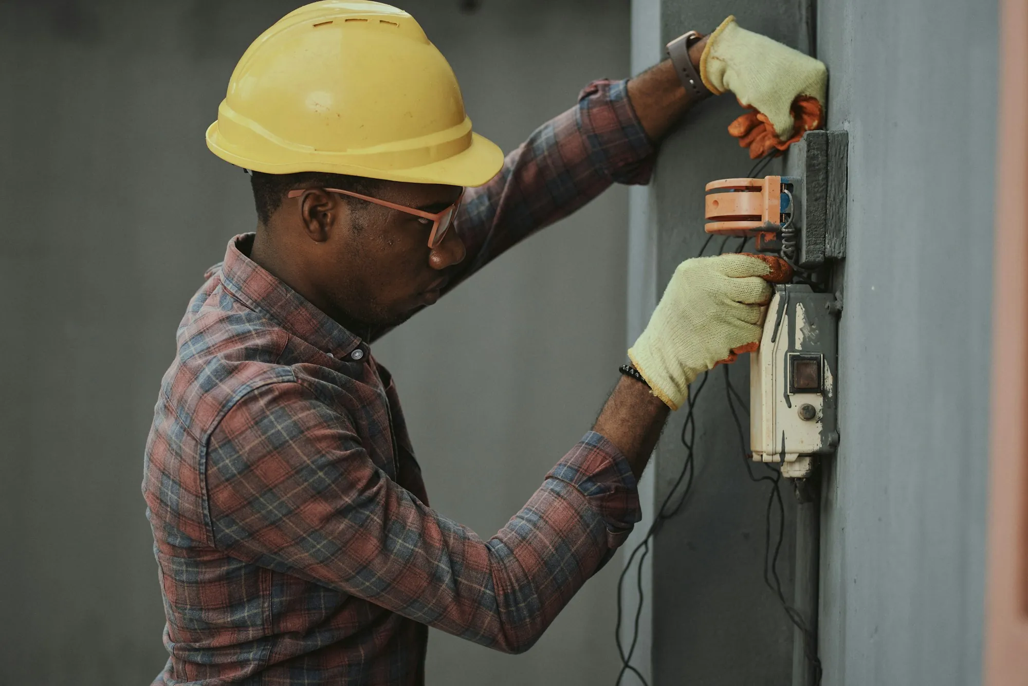 An electrician working at an exterior electrical enclosure